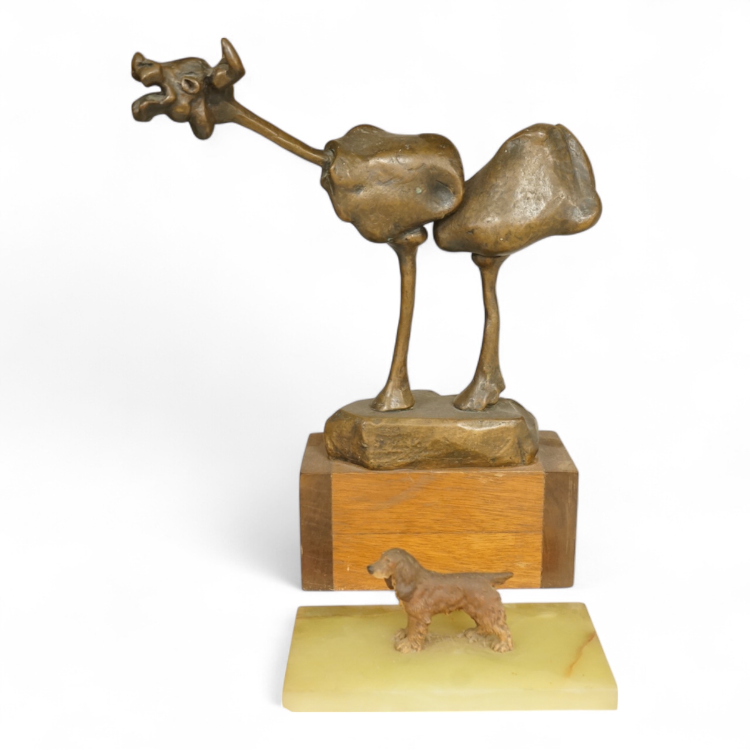 An abstract bronze model of a cow, 34cm and an Art Deco green onyx box, the lid surmounted with a cold painted bronze spaniel, 16.5cm wide.